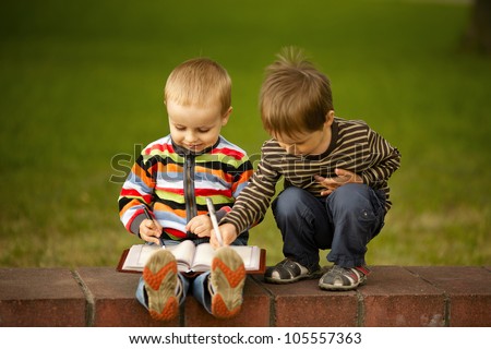 two boys write in a notebook