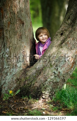 little pretty girl climbing tree in the park