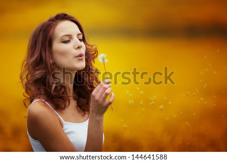 Happy Beautiful Woman Blowing Dandelion In The Field