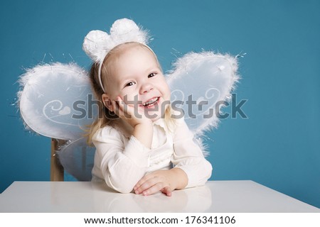 Cute little girl with butterfly costume on blue background