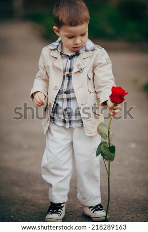 small and pretty boy hold red rose in hand