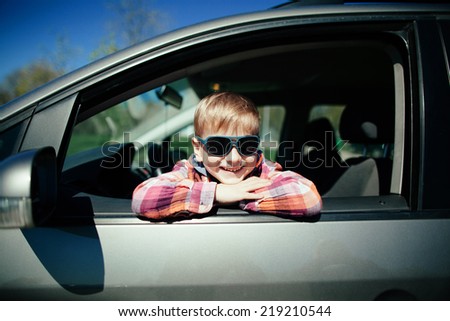 little cute boy driving fathers car at springtime