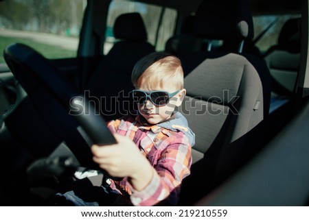 little cute boy driving fathers car at springtime