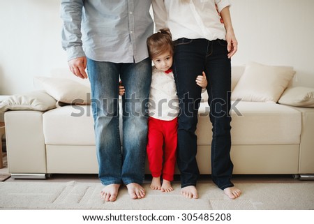 little girl hugging mom and dad for legs