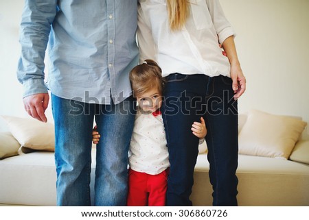 little girl hugging mom and dad for legs