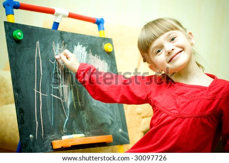 Girl draws with chalk on the blackboard