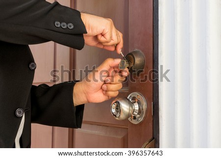 locksmith in black suit repair the lock on wood door