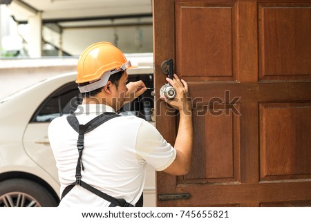 locksmith with safety helmet try to install knob on wood door for home service