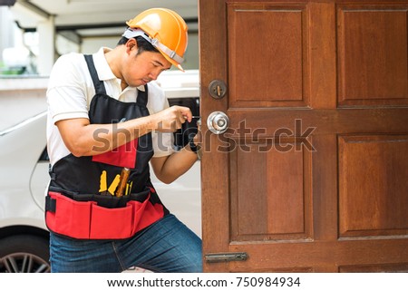 locksmith repair silver handle lock on wood door home with handyman tool and safety helmet