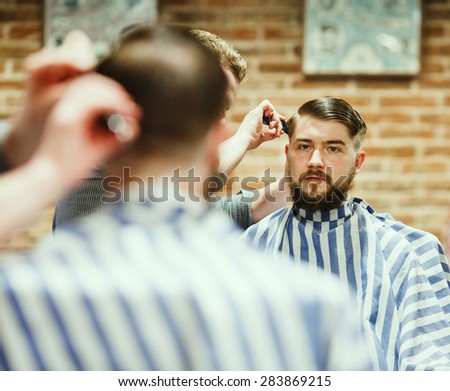 Barber cutting bearded brutal man, reflection in the mirror