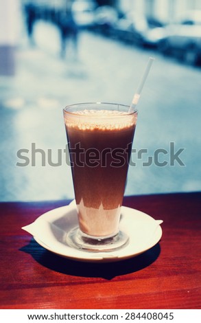 Cup of Chocolate milk on brown wooden table, against the background of window