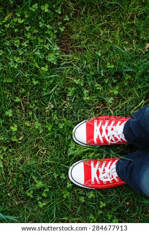 Red sneakers shoes walking on grass plot top view, Canvas shoes walking on grass plot