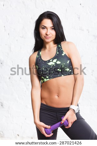 Athletic young brunette woman with strong abs and flat belly, in