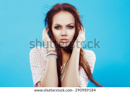 Close up portrait of attractive gorgeous model with beautiful long brown fluttering hairs. In nice clothes posing in the studio, on blue background.