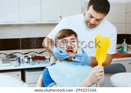 Young male patient looking at mirror in the dentists office