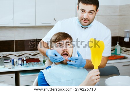 Young man looking at mirror in the dentists office