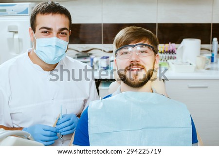 Happy dentist in medical mask and happy patient, at dental office.