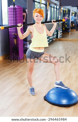 Slim redhead fitness girl with short haircut is doing exercises in the gym