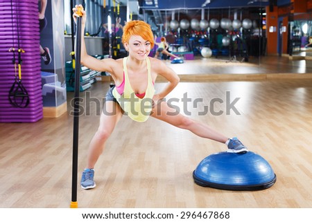 Fitness girl with short haircut is doing exercises near the mirror in the gym