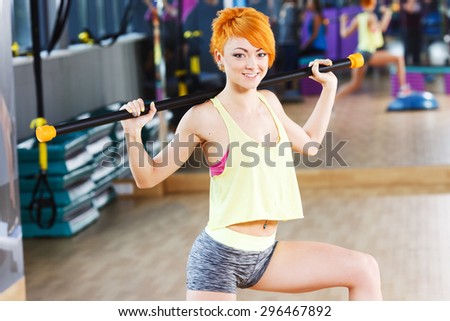 Redhead fitness girl with short haircut is doing exercises in the gym