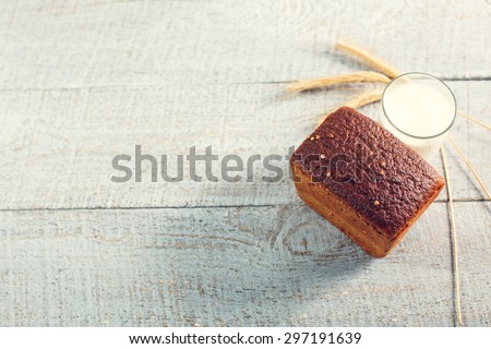 Fresh baked bread with milk and spikelets of wheat on a white wooden boards. rustic style. close up