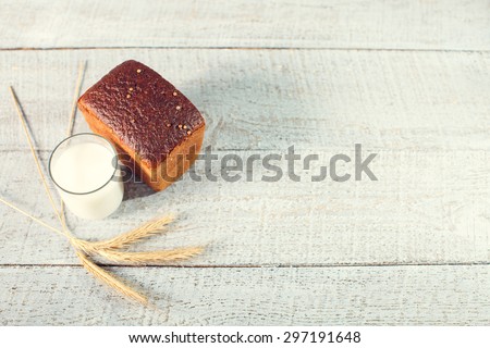 Homemade bread with spikelets of wheat and glass of milk on a wooden boards. close up