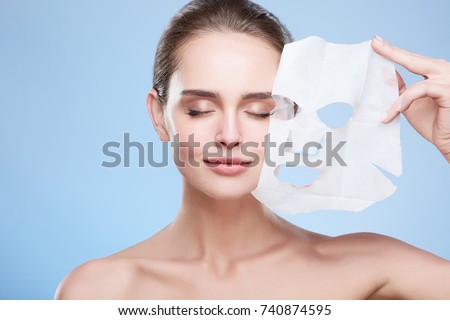 Beauty concept, head and shoulders of girl removing mask from face, face pack. Young woman with pure skin, closed eyes and smiling. Studio, grey background
