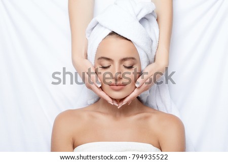 Young  girl with thick eyebrows and perfect skin at white background, towel on head, beauty photo concept, skin care, spa concept, treatment, facial massage.