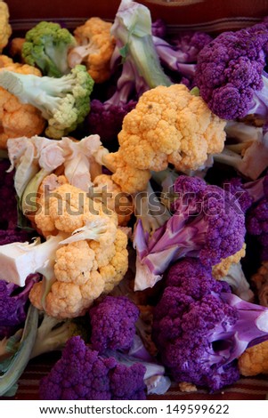Bunches of fresh yellow, white, purple and green cauliflower heads at the farmers market