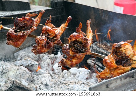 chicken being roasted on a spit over a fire