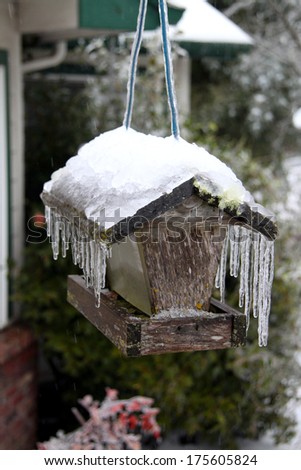 bird feeder covered in ice with icicles and snow