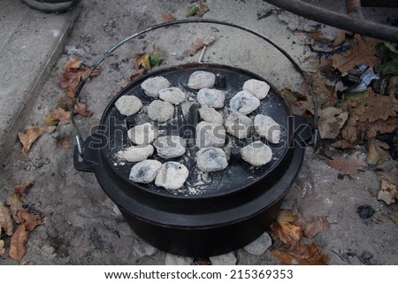 dutch oven with coals on top in a fire pit
