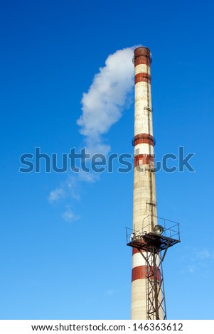 Smoke from a factory chimney against blue sky