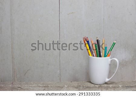 color pencils broken on White Mug lay on the cement.