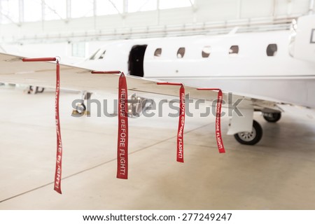 Airplane in Hangar with remove before flight Labels in red