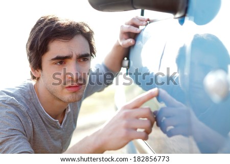 View of a Young man looking for scratches on his car
