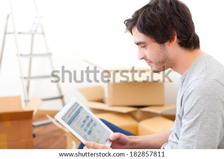 View of a handsome young man in his new flat using tablet