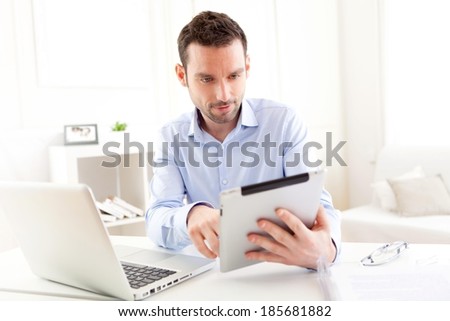 View of a Young business man working at home on his tablet