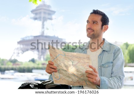 Young attractive tourist reading map in Paris, France