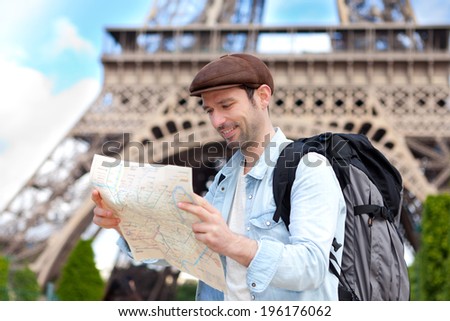 Young attractive tourist reading map in Paris, France