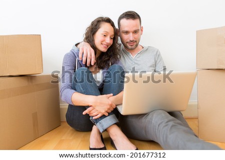 View of a Young couple using laptop while moving in new flat