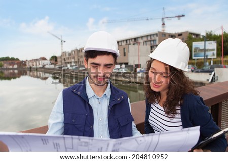 Architect woman and construction site supervisor watching plans