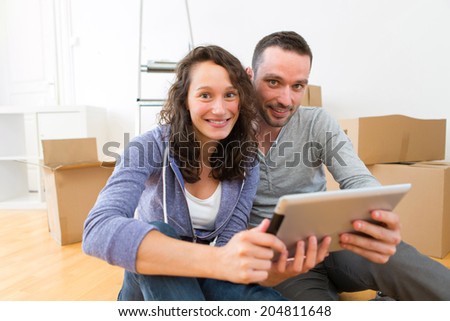 View of  Young couple using tablet while moving in new flat