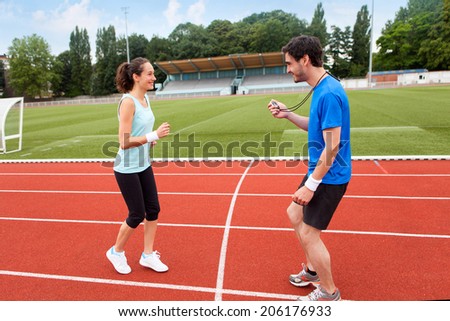 Sport coach training a young attractive woman on a stadium