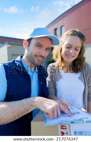 View of a Young attractive woman signing on delivery paper