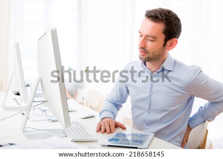 View of a Young attractive man got a back pain at the office