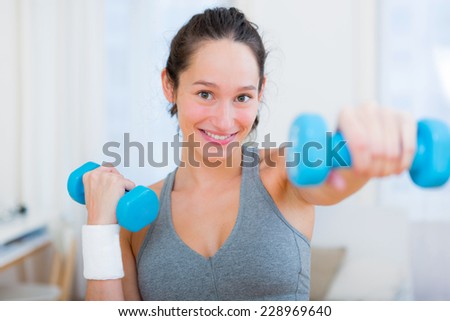 View of a Young attractive girl doing exercise at home with dumbell