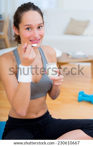 View of a Attractive sportive woman eating yogurt after sport