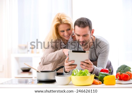 View of a Young attractive couple reading recipe on a  tablet