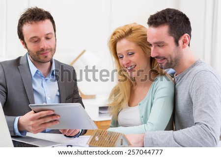 View of a Real estate agent present project on tablet to a young couple